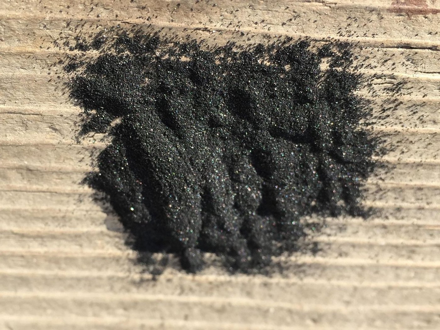 A pile of loose black powder on a wood plank